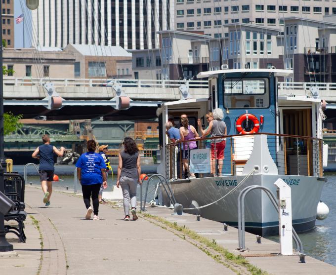 Photograph of people walking alongside the Genesee River in downtown Rochester.