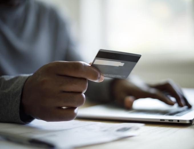 Photo of someone holding a credit card and typing on a computer.